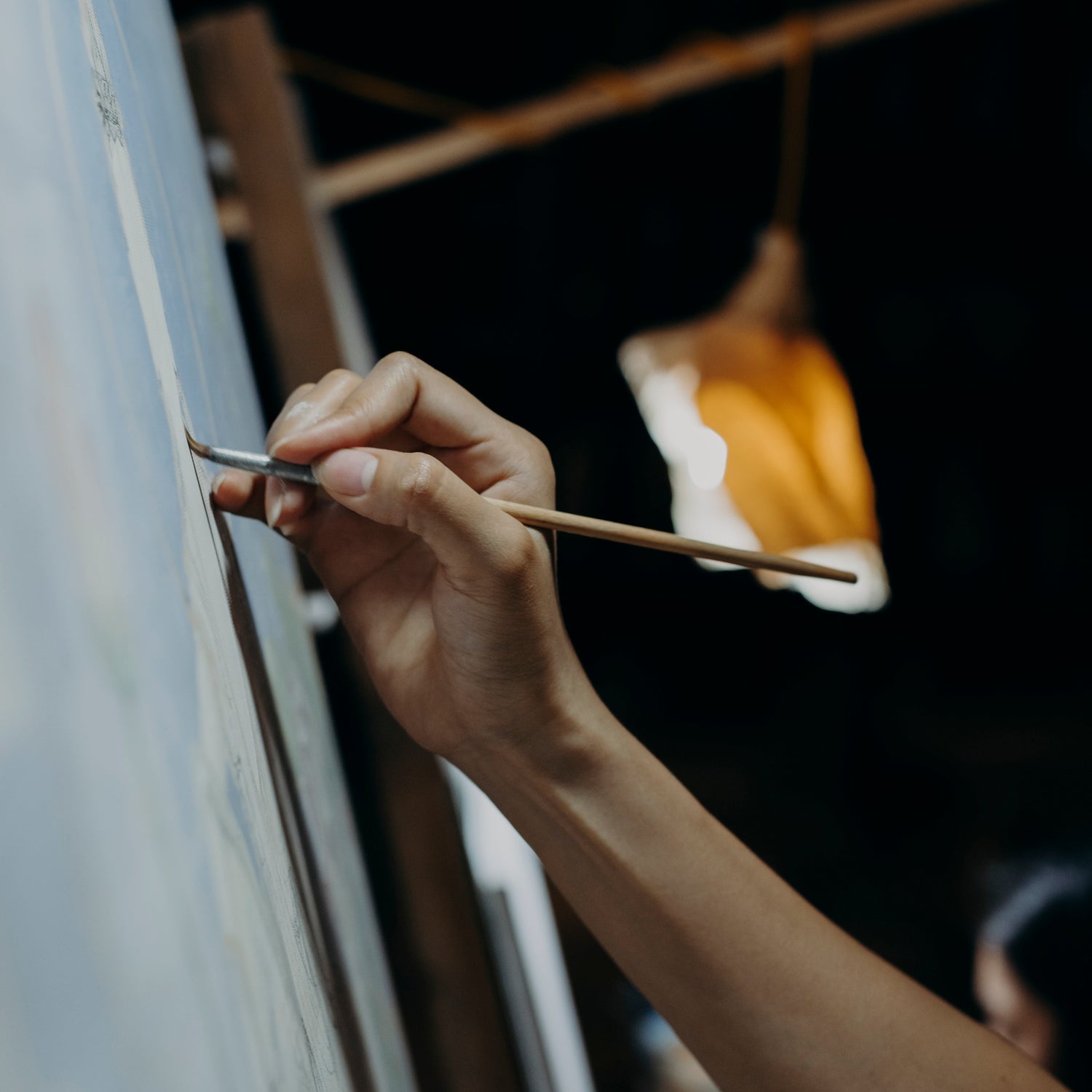 Person painting on a large canvas with a brush, blurred background, for Filthy Rebels, a new print on demand store that funds the fight to end global hunger.